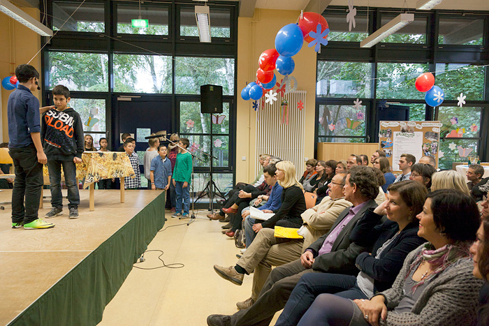 Foto: 'Erwachsene sitzen vor einer Bühne auf der Kinder ein Theaterstück aufführen