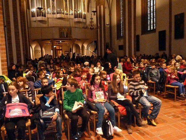 Foto: Kinder sitzen auf Stuhlreihen in einer Kirche