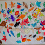 Foto: viele bunte selbst gemalte Herbstblätter kleben auf einer weißen Wandzeitung mit bemaltem Igel