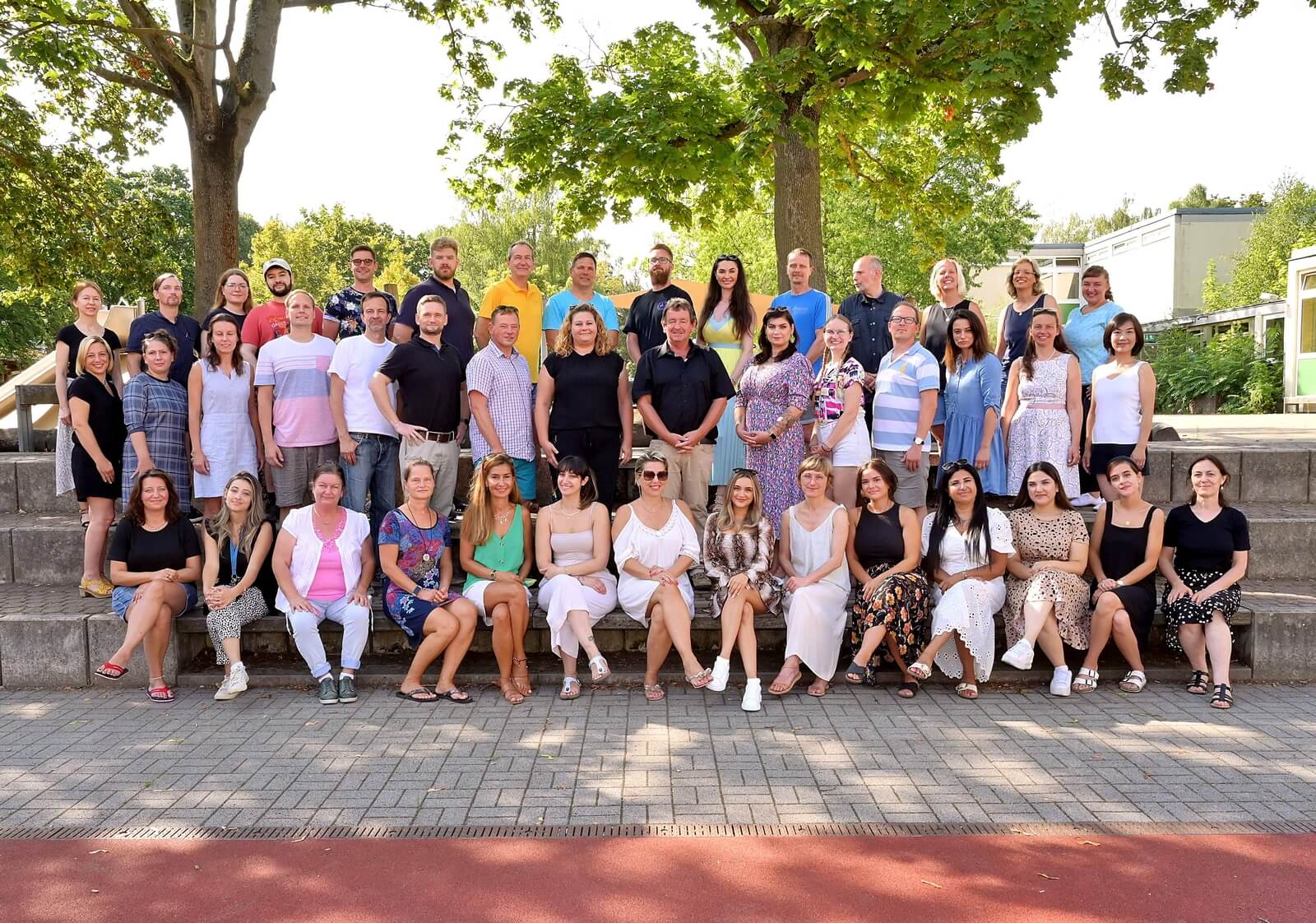 Personal Askanier-GS 2022-2023 Foto: Gruppe von Männern und Frauen in Gruppenfotopose auf eine Tribüne mit Blick zum Betrachter. Vorderste Reihe sitzt.